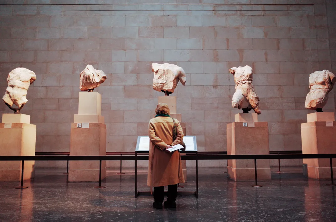 A woman stands in front of a selection of Elgin Marbles on display at the British Museum