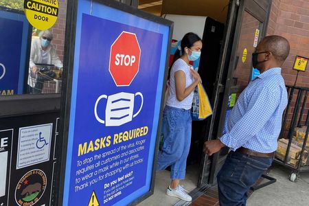 Individuals wear masks while shopping at a grocery store in Los Angeles. Masks help prevent breakthrough infections.