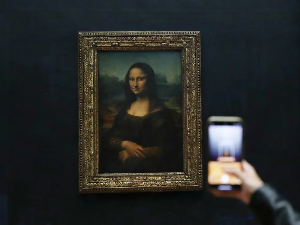 Visitor takes a photo of the Mona Lisa
