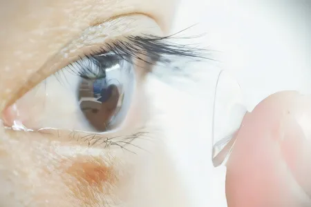 A study participant puts in a contact lens. Researchers developed lenses with nanoparticles that convert infrared wavelengths into visible light that humans can perceive.
