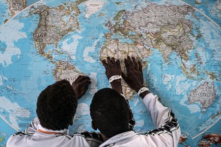 Gambian asylum seekers look at a map while waiting in an Italian migrant center. 