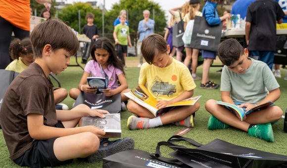 A group of children sit on the grass to read silently to themselves