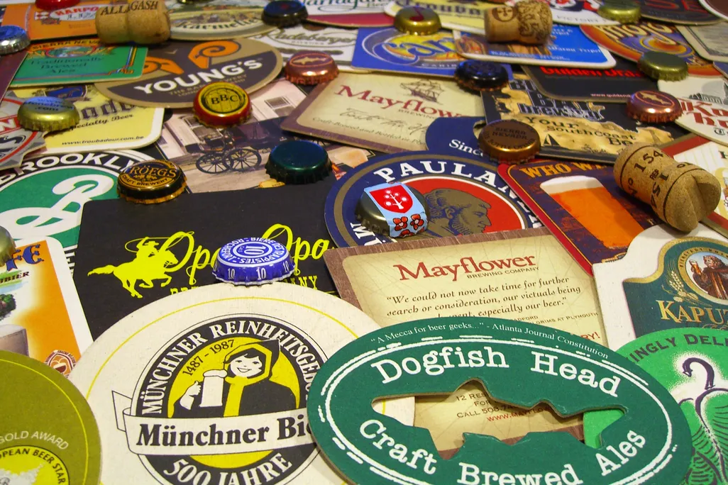 A pile of various beer coasters, wine bottle borks and metal beer bottle caps