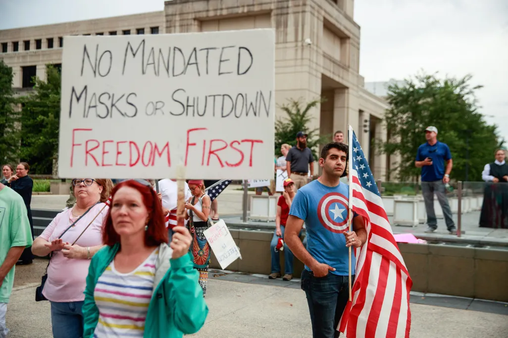 At an anti-mask rally, a protester holds a placard saying No Mandated Masks or Shutdown Freedom First 
