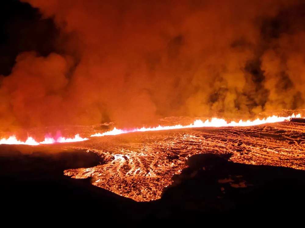 glowing lava erupting from a fissure and spreading across the ground