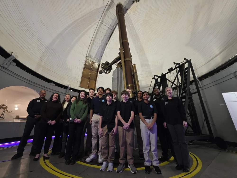 A group smile in front of the Great Refractor telescope