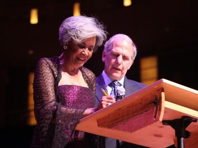 Nancy Wilson signs the deed of gift, donating two of her gowns to the American History Museum, alongside museum director Brent Glass, at the Music Center at Strathmore.
