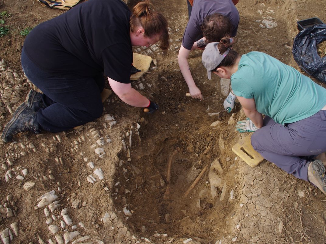 A group of people excavate a grave