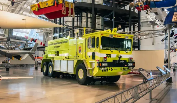 Yellow rescue truck on display in museum setting.