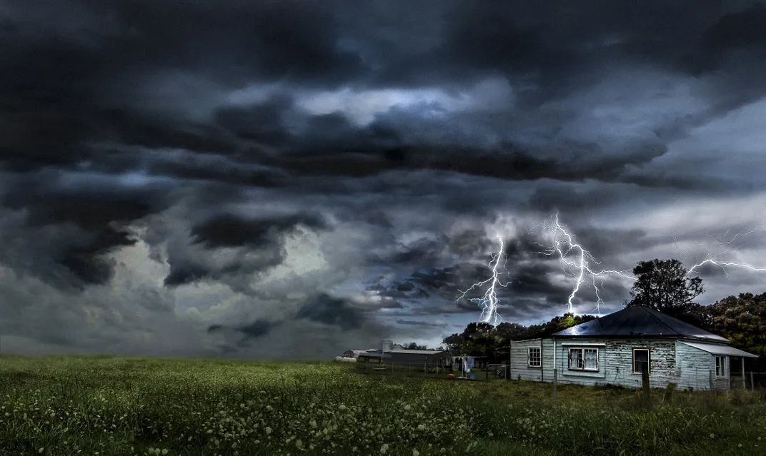 Lighting strikes on a field near a house