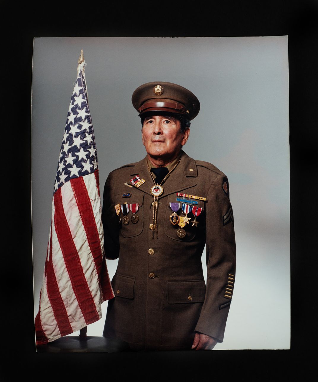 Joseph O. Quintero stands in uniform holding his handmade U.S. flag