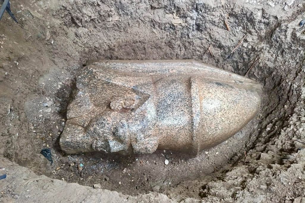 The head of a statue in a hole in the ground