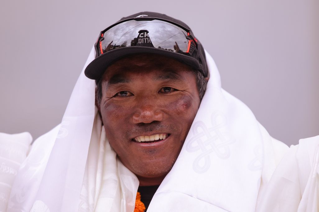 A man wearing a hat with glasses on them smiles