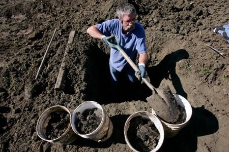 A man fills up buckets with dirt while hunting for diamonds at Crater Diamonds State Park in Murfreesboro, Arkansas.