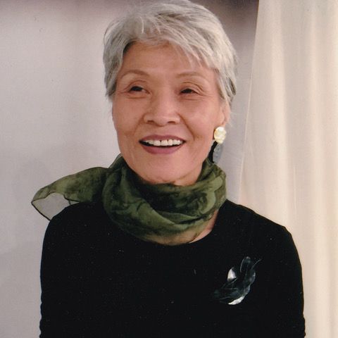 Reiko Ishiyama, a Japanese American jeweler, wears a black shirt and a green scarf.
