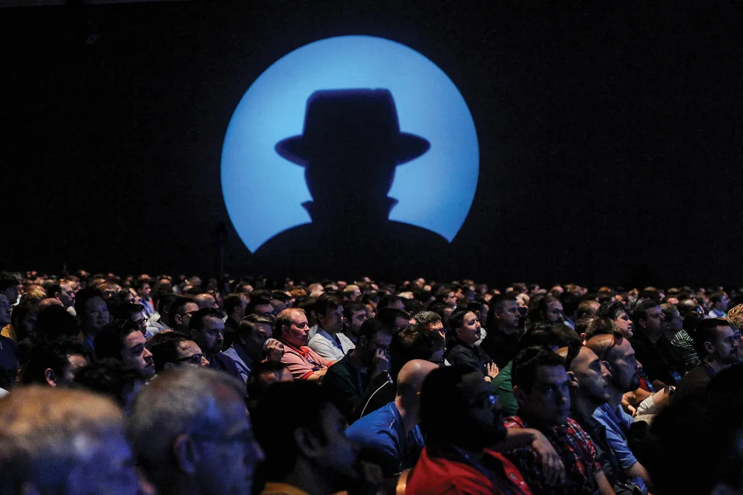 people sitting while an image of a silhouette in a hat is projected