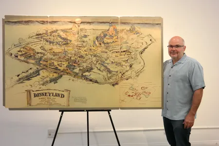 Mike Van Eaton of Van Eaton Galleries, posing with Disney's early map of Disneyland