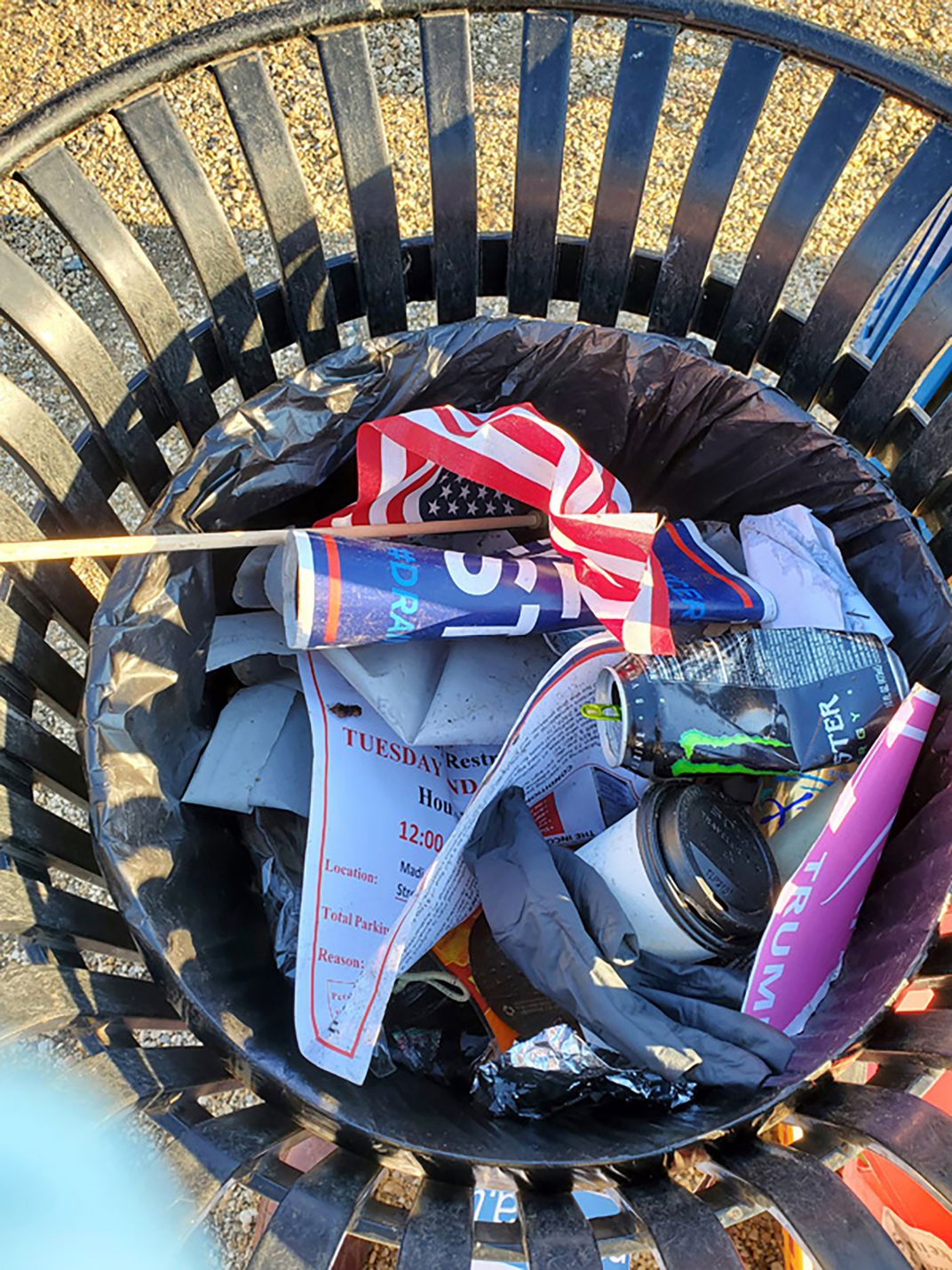 trash can holding an american flag, signs and papers