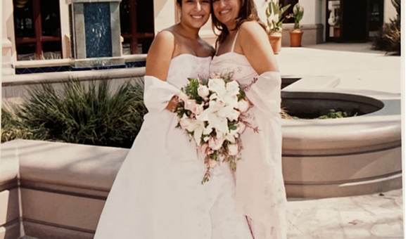 Quinceañera (fifteen-year-old girl) wearing a long strapless dress and posing by her mother's side.