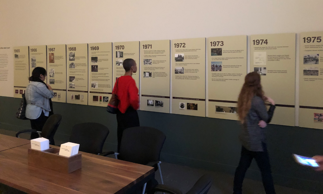 A photograph of people in a museum looking at a timeline wall.