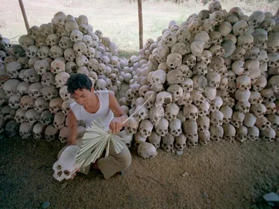 A man cleans a skull near a mass grave at the Chaung Ek torture camp run by the Khmer Rouge in this undated photo.