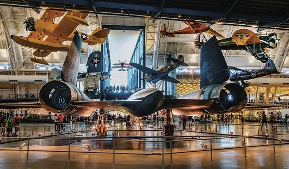 Multiple aircraft are on exhibit, including five suspended from the ceiling. Displayed on the floor is the Lockheed SR-71, viewed from the rear--the exhaust nozzles of the powerful jet engines in full view.