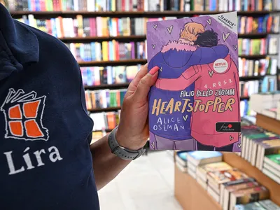 A staff member holds a copy of Heartstopper, an LGBTQ teen romance,&nbsp;at Lira&#39;s shop in Budapest.