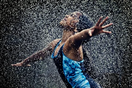 A girl runs through sprinkles of water to cool off on a hot summer day.

