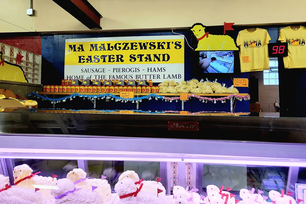 Ma Malczewski's Easter Stand. Above are shirts and a banner featuring the phrase Home of the Famous Butter Lamb. Butter lamb sculptures are visible in the refrigerated display below.
