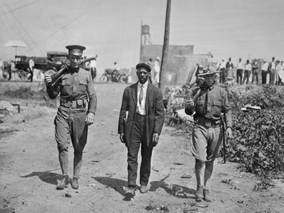 Two National Guard escort an African-American man in the tense summer weeks of 1917 in East St. Louis, Illinois.