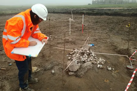 Archaeologists uncovered human remains and a mysterious arrangement of boulders at the site in the Shetland Islands.