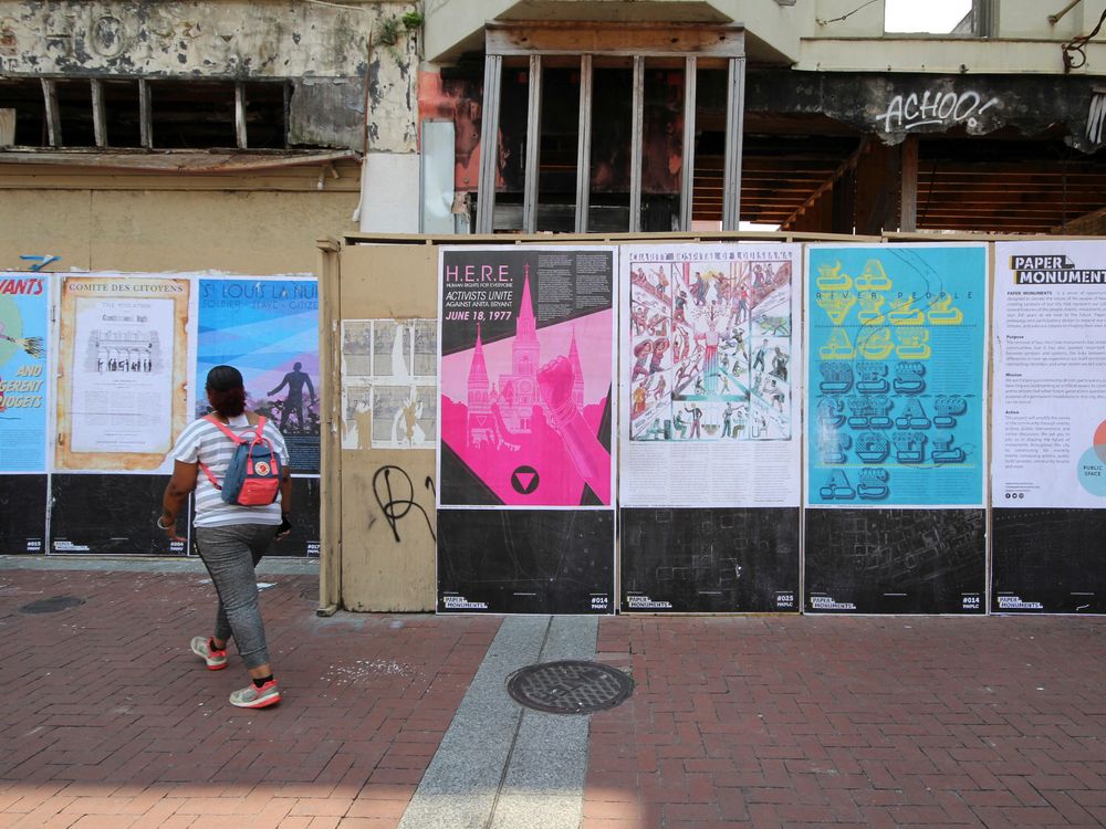 A person looking at a wall of posters in front of a building under construction