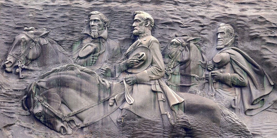 A stone carving of three men on horseback, carved into the side of a granite mountain face