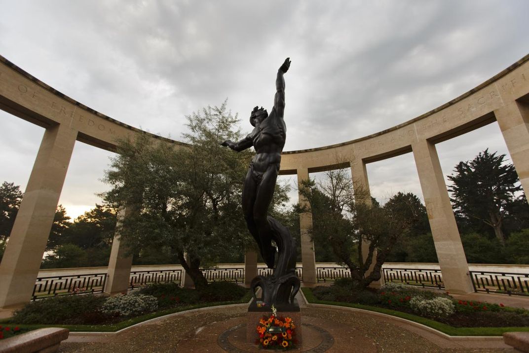 Statue of man emerging from waves and reaching towards the sky