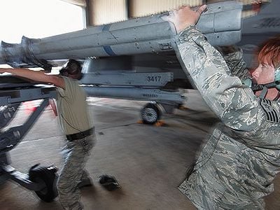 Staff Sergeant Michelle Torrey, right, with Master Sergeant Brett Kitzman load an AIM-120 missile onto an F-16.