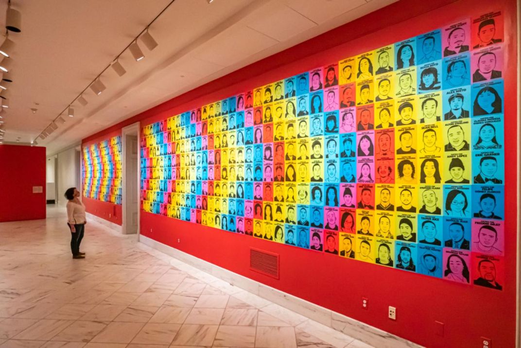 A person looks at a hallway covered in a collage of portraits