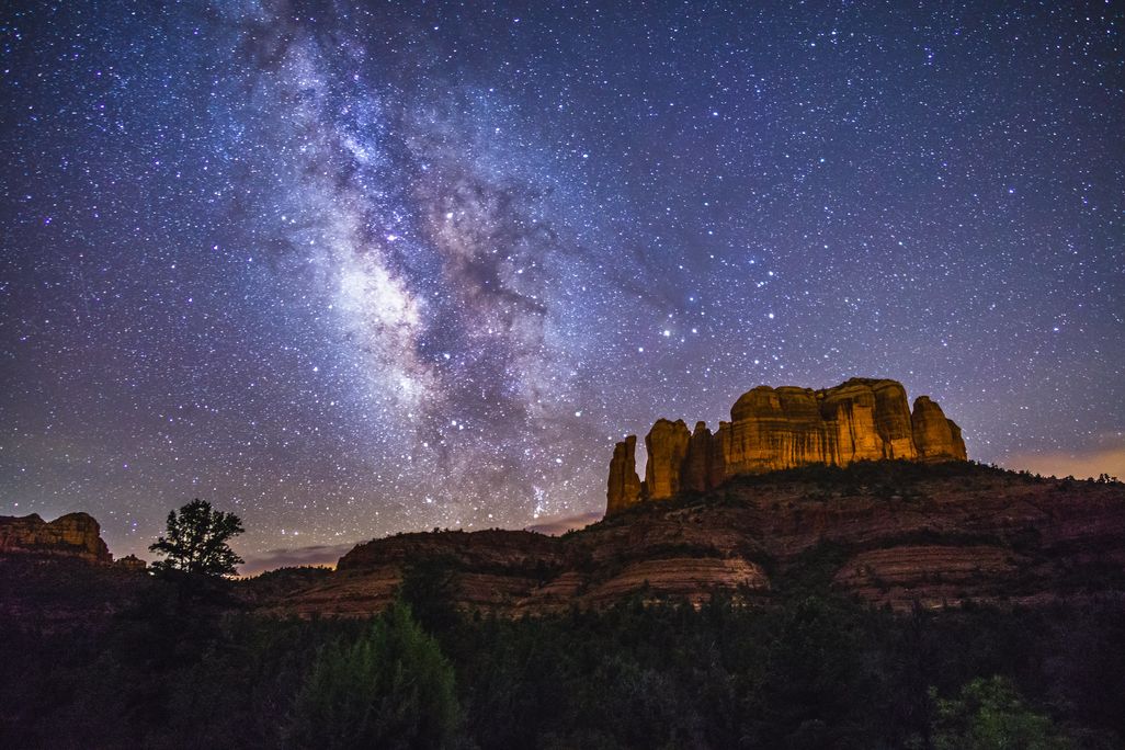 milky way over a rock formation on a mountain