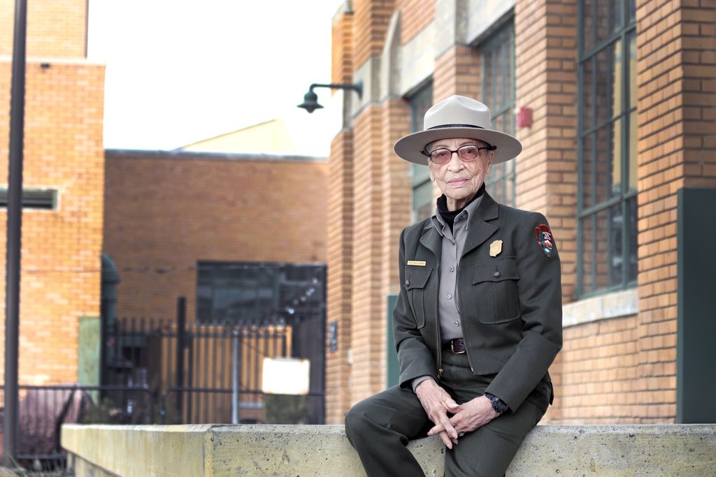Betty Reid Soskin, an elderly Black woman in a green-gray NPS ranger uniform with a wide-brimmed hat