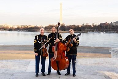 Three men with string instruments pose for a photo