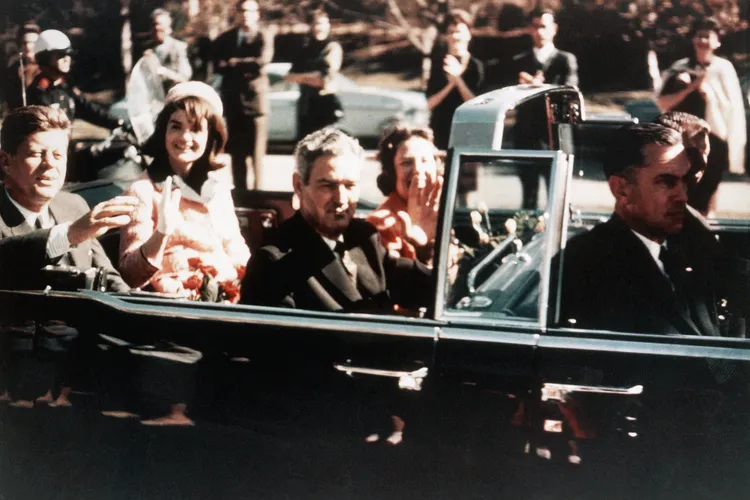 John F. Kennedy and Jackie Kennedy ride the presidential limousine through the streets of Dallas, Texas