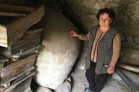 Asli Saghatelyan stands next to her father-in-law’s 240-gallon karas, a clay vessel traditionally used in Armenia, until recently, for storing and fermenting homemade wine.