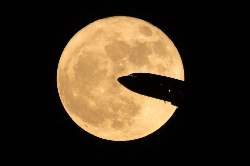 A full moon with the partial silhouette of a plane in front of it