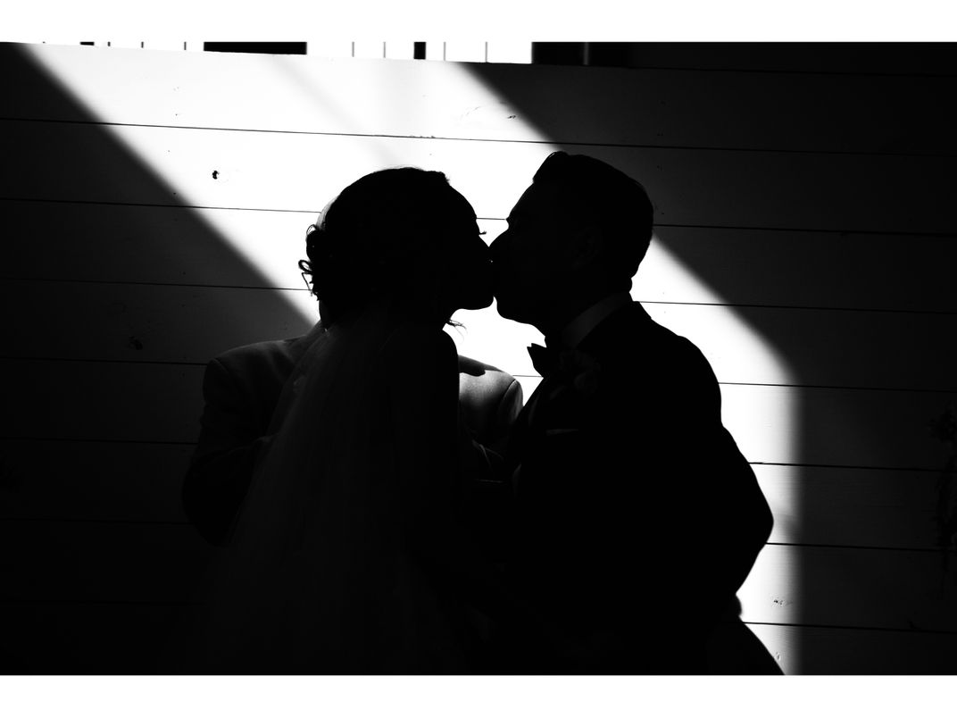 OPENER - A wedding guest captures a loving moment between a silhouetted bride and groom.