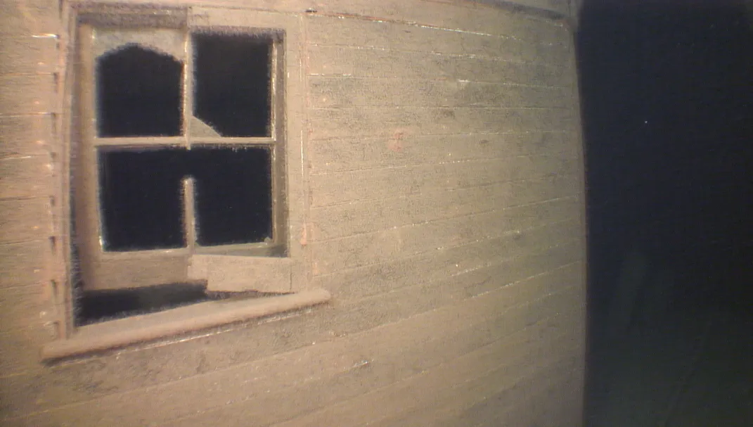 The well-preserved square window on the side of a main cabin, underwater with the glass long-gone