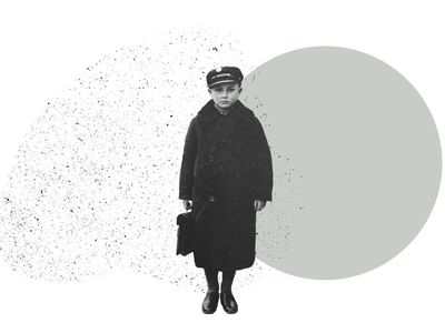 A boy in a long wool coat and hat holds a small case