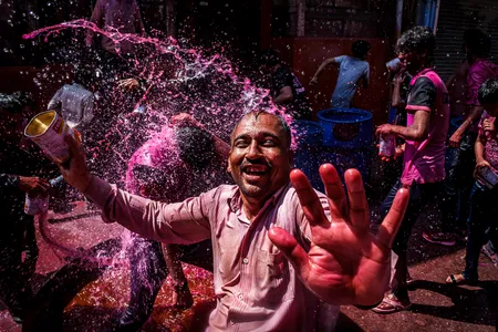 A reveler enjoys a playful and colorful water war in the streets of Jodhpur during the Holi festival.

