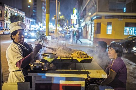 A Lima street vendor dishes up anticucho, grilled skewers that are traditionally prepared with marinated beef heart or tongue. It is a culinary tradition probably started by enslaved Africans here during the Spanish colonization.
