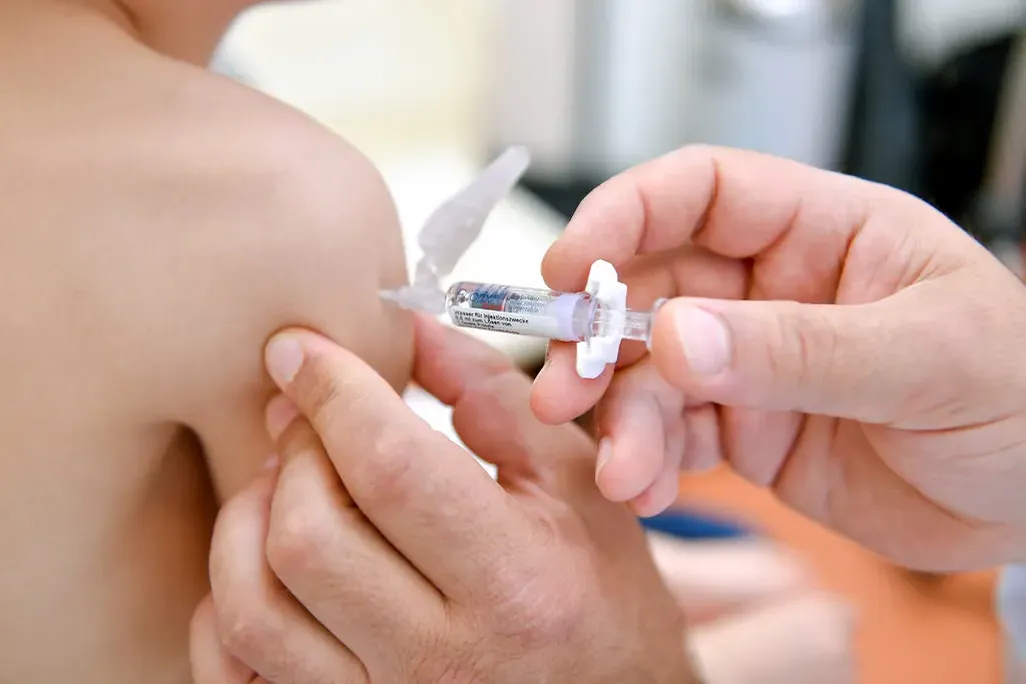a person administers a shot in the arm of a child