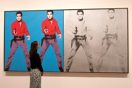 A gallery assistant poses with Andy Warhol's Elvis 1 and 2 1963-4 during a press preview for Tate Modern's retrospective on March 10, 2020.