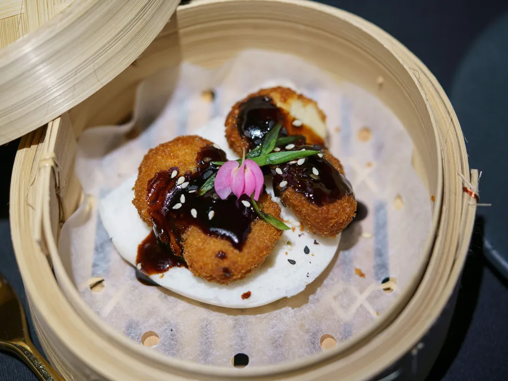 Chicken nuggets made from lab-grown meat covered with a sauce and flower garnish.